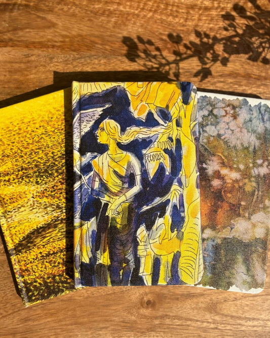 Three notebooks with different covers on a wooden surface