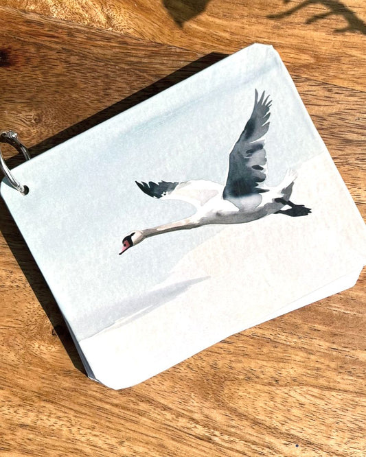 Small journal with a swan design on a wooden surface