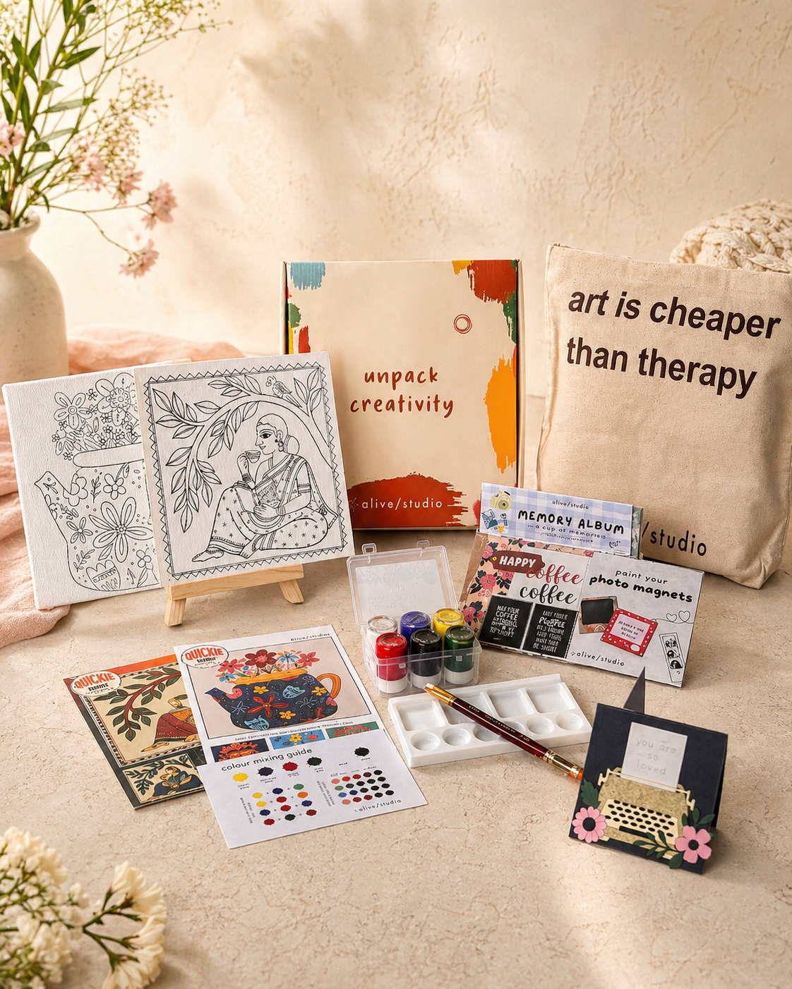 Collection of art supplies and decorative items on a light surface with flowers.